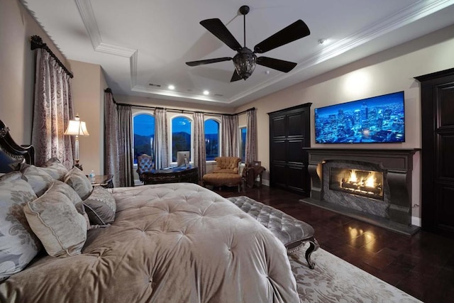 bedroom with ceiling fan, a raised ceiling, ornamental molding, and dark wood-type flooring