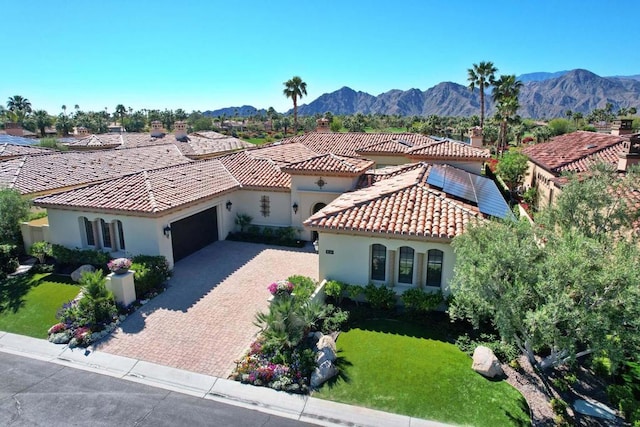 view of front of property featuring a mountain view, solar panels, a garage, and a front yard