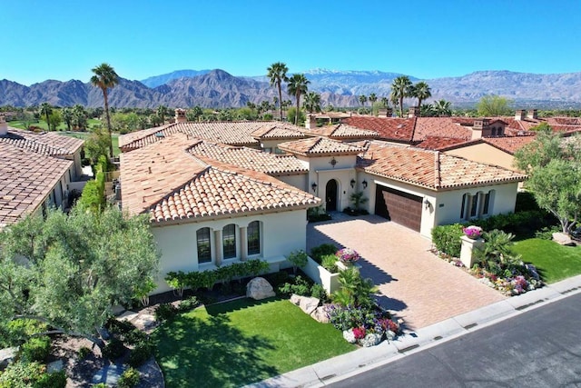 mediterranean / spanish home featuring a mountain view, a front yard, and a garage