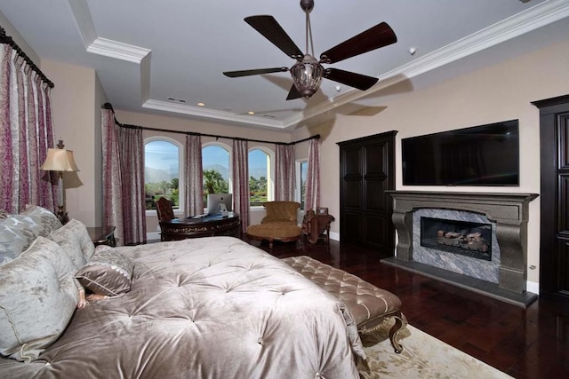 bedroom featuring a fireplace, dark hardwood / wood-style flooring, ceiling fan, and crown molding