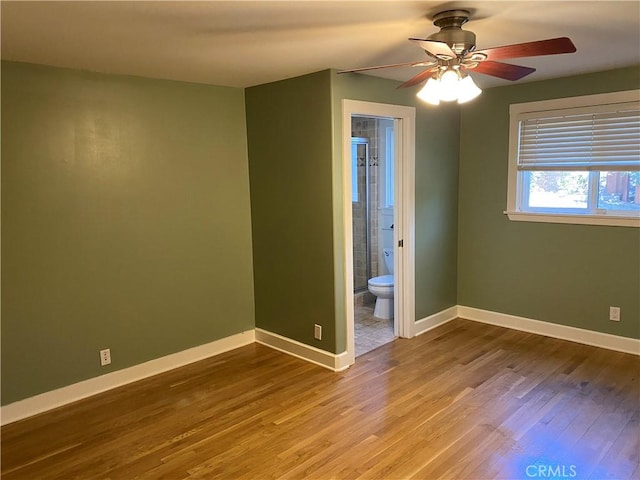 unfurnished bedroom with hardwood / wood-style floors, ensuite bathroom, and ceiling fan