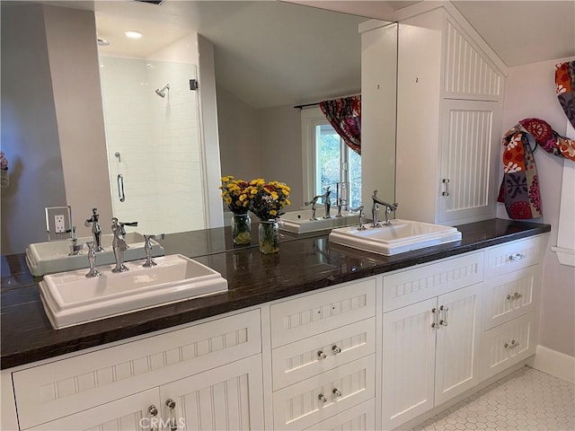 bathroom with tile patterned floors, a shower with door, and vanity