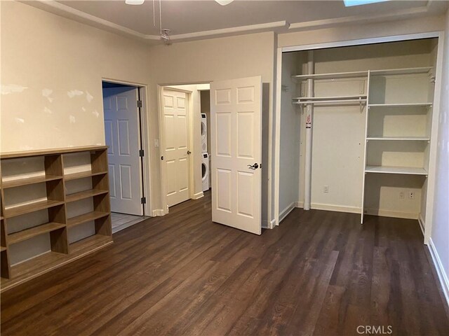 unfurnished bedroom featuring stacked washer / drying machine, dark hardwood / wood-style floors, and a closet