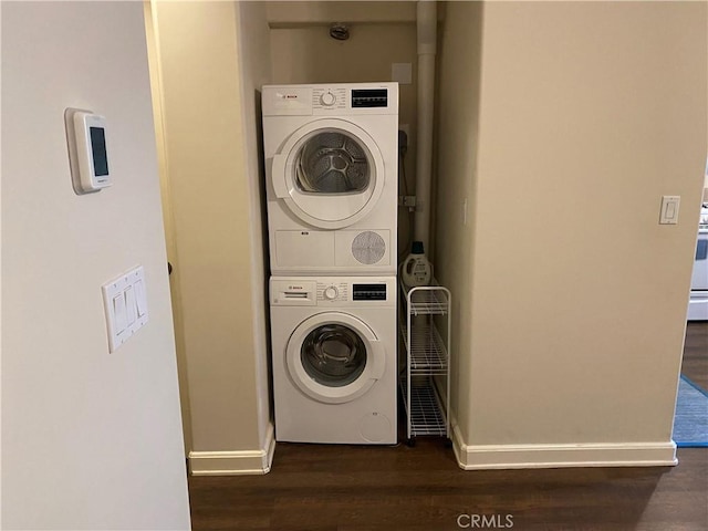 clothes washing area with dark hardwood / wood-style floors and stacked washer and clothes dryer