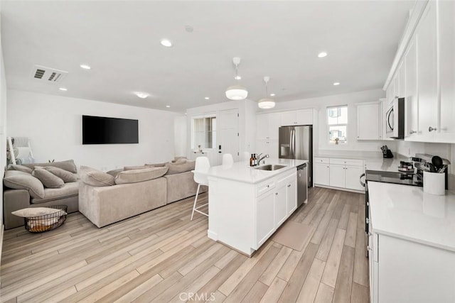 kitchen featuring a center island with sink, white cabinetry, and light hardwood / wood-style flooring