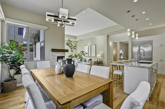 dining space with sink, a fireplace, and light wood-type flooring