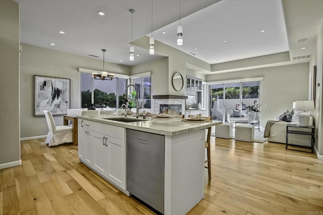 kitchen featuring sink, hanging light fixtures, dishwasher, a kitchen island with sink, and white cabinets