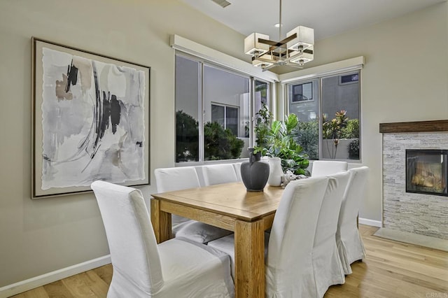 dining room with a chandelier, a fireplace, and light hardwood / wood-style floors