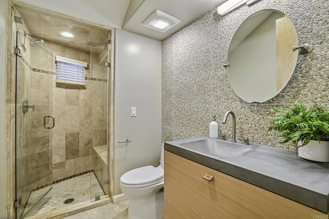 bathroom featuring tile patterned floors, toilet, a shower with shower door, vanity, and decorative backsplash