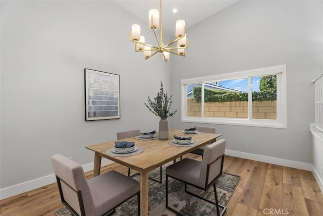 dining room with a chandelier, light wood-type flooring, and high vaulted ceiling