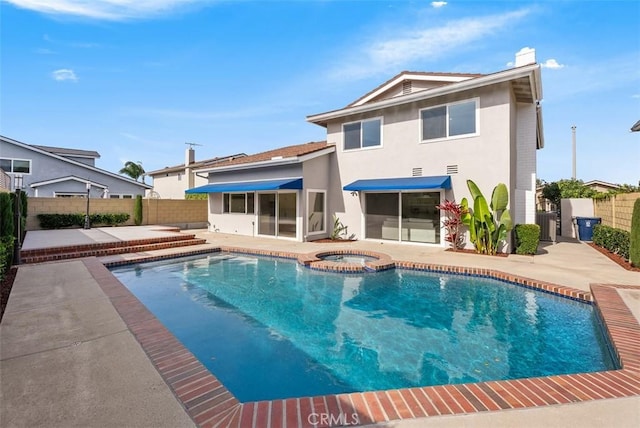 rear view of property with a patio area and a swimming pool with hot tub