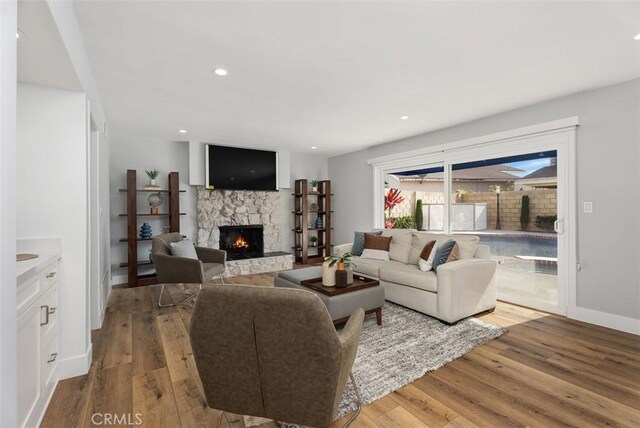 living room with light wood-type flooring and a stone fireplace