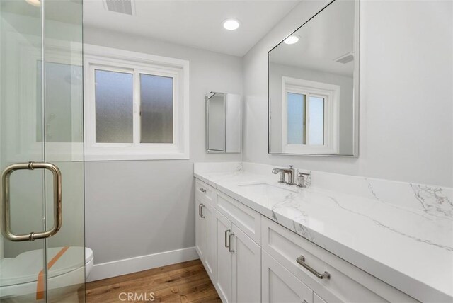 bathroom with hardwood / wood-style floors, vanity, toilet, and a shower with shower door