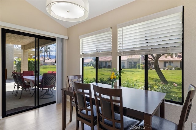 dining space featuring light wood-type flooring and vaulted ceiling