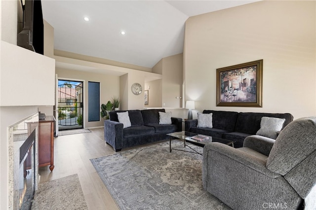 living room with high vaulted ceiling and light hardwood / wood-style flooring