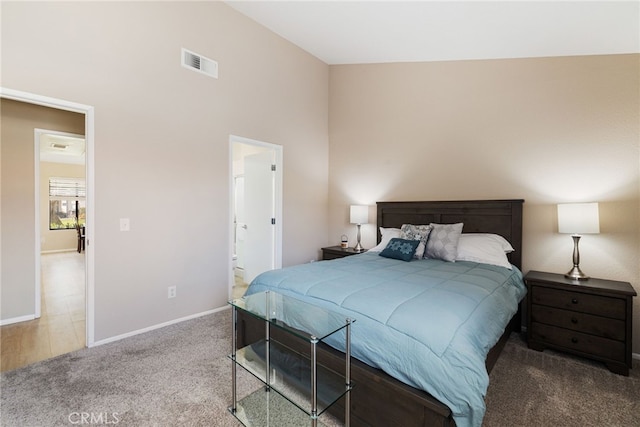 bedroom with ensuite bath, carpet, and vaulted ceiling