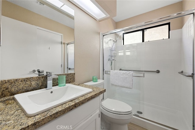 bathroom with a shower with door, vanity, and toilet