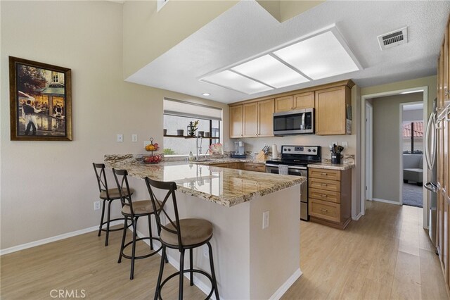 kitchen featuring kitchen peninsula, appliances with stainless steel finishes, a wealth of natural light, and a breakfast bar area