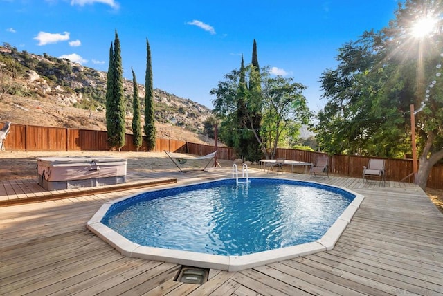 view of pool with a deck with mountain view and a hot tub