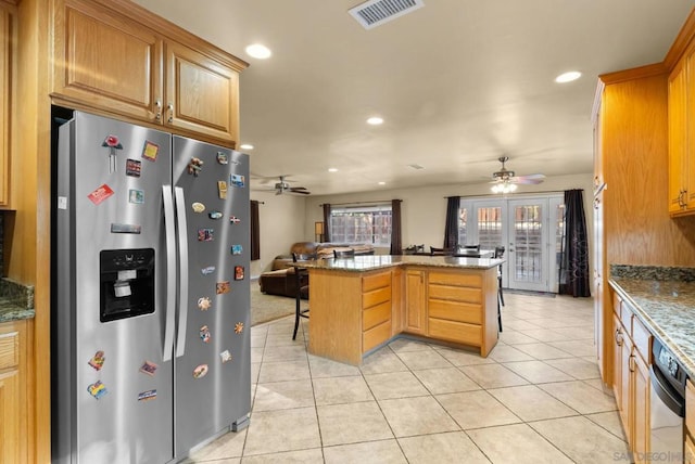 kitchen with french doors, kitchen peninsula, dark stone counters, a breakfast bar area, and appliances with stainless steel finishes