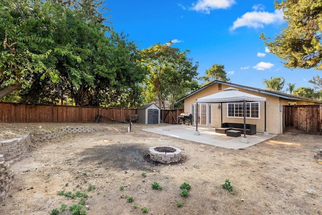 back of house with a shed, a patio area, and a fire pit