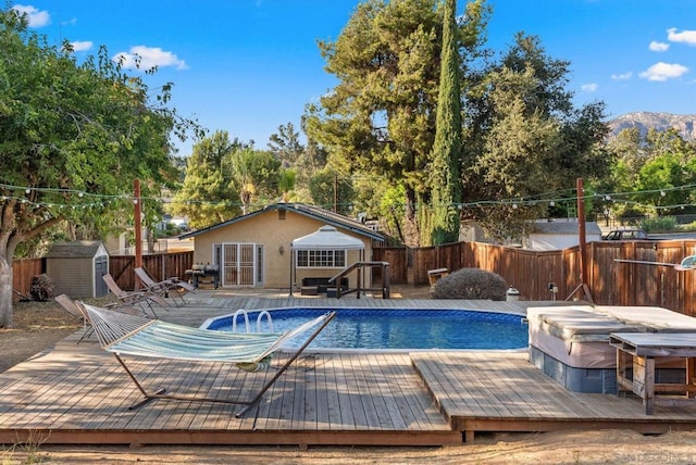 view of swimming pool featuring a hot tub, a shed, and a deck