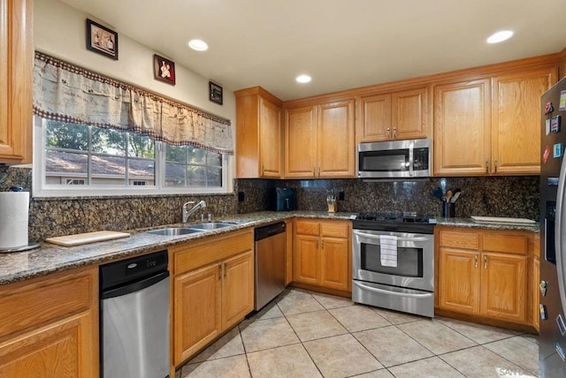 kitchen with stainless steel appliances, dark stone counters, and sink