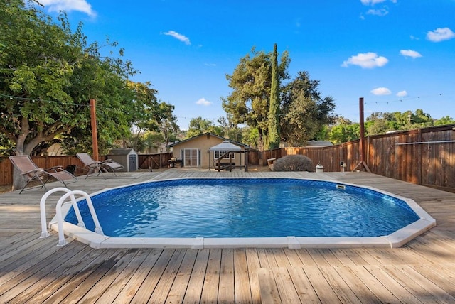 view of swimming pool featuring a wooden deck and a storage shed