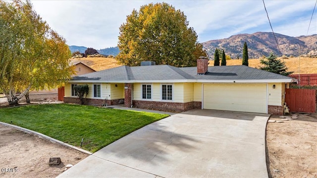 ranch-style house featuring a mountain view, a garage, and a front lawn