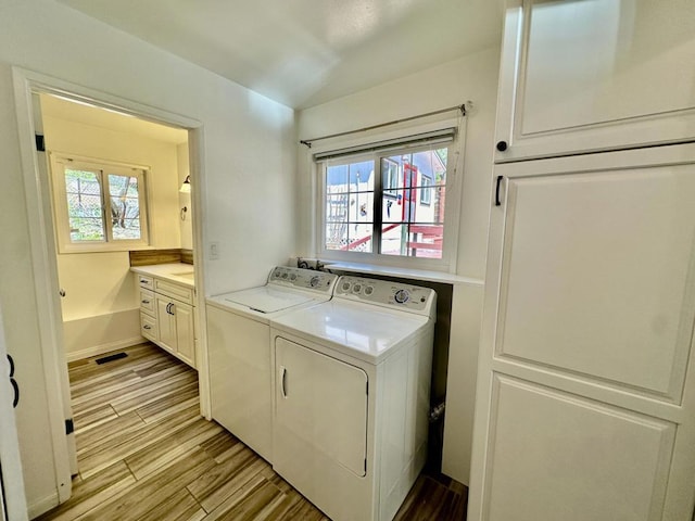 clothes washing area featuring washing machine and dryer, plenty of natural light, and light wood-type flooring