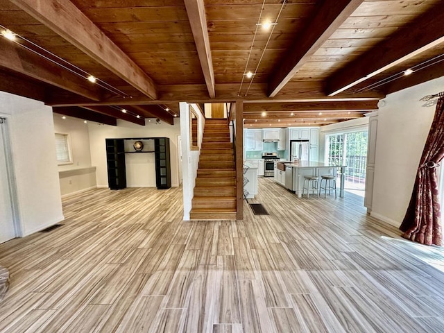 interior space featuring beamed ceiling, appliances with stainless steel finishes, light hardwood / wood-style flooring, and wood ceiling