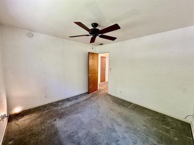 empty room featuring ceiling fan and dark colored carpet