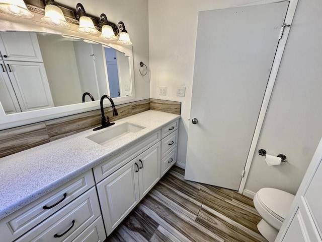 bathroom featuring toilet, vanity, and hardwood / wood-style flooring