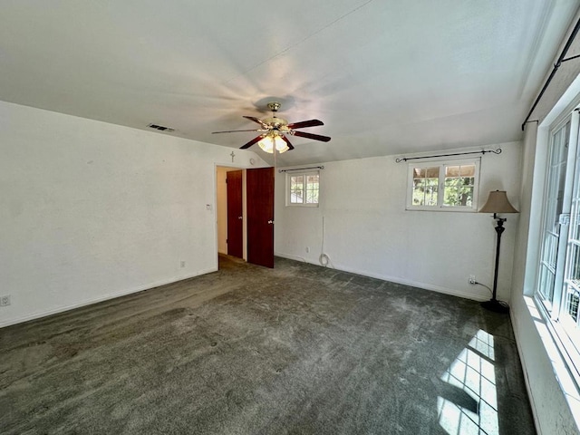 spare room featuring ceiling fan and dark carpet