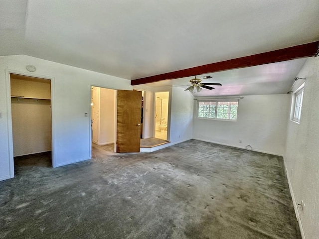 unfurnished bedroom featuring a walk in closet, ceiling fan, dark colored carpet, lofted ceiling with beams, and a closet