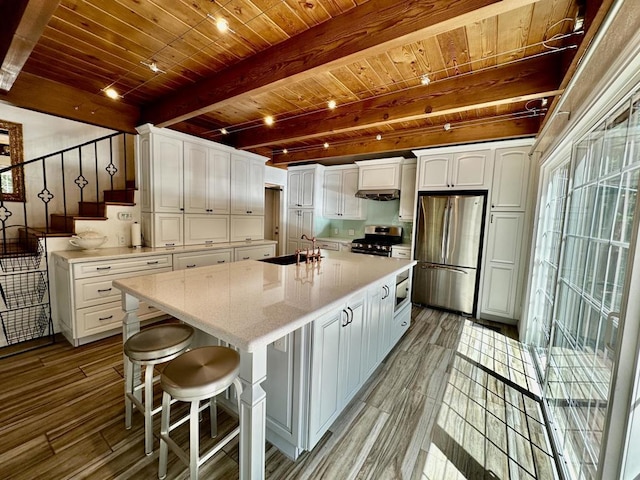 kitchen with appliances with stainless steel finishes, light wood-type flooring, beam ceiling, a center island, and white cabinetry