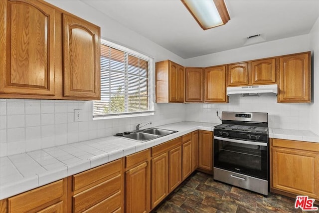 kitchen featuring tile counters, stainless steel range with gas cooktop, sink, and tasteful backsplash