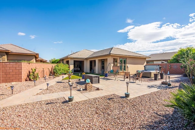 back of house featuring a jacuzzi and a patio