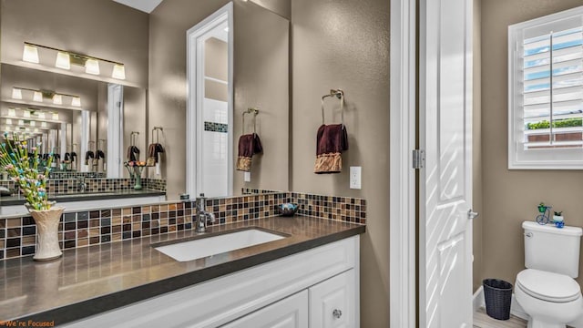 bathroom featuring vanity, toilet, and tasteful backsplash