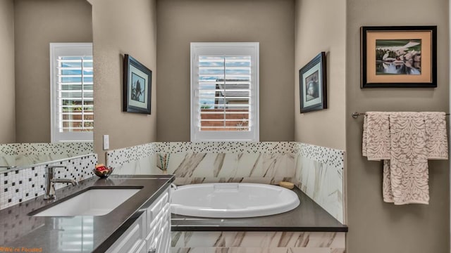 bathroom with vanity, a healthy amount of sunlight, and tiled bath