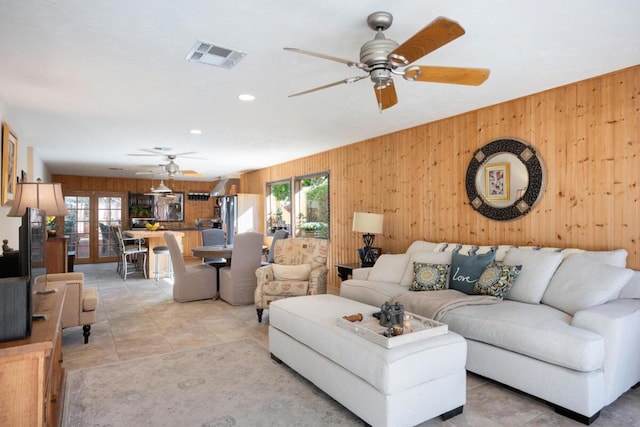 living room with ceiling fan and wooden walls