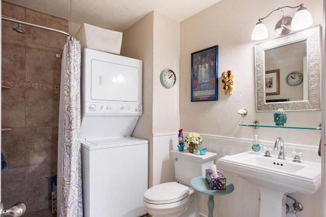 bathroom featuring sink, stacked washer / drying machine, toilet, and a shower with shower curtain