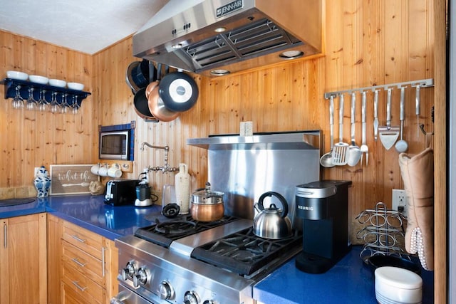 kitchen featuring stainless steel range, exhaust hood, and wood walls