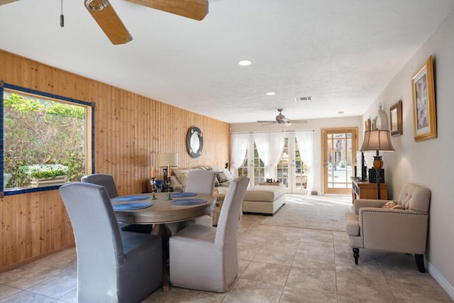 dining room with ceiling fan, a wealth of natural light, and wooden walls