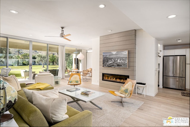 living room featuring ceiling fan, a fireplace, and light wood-type flooring