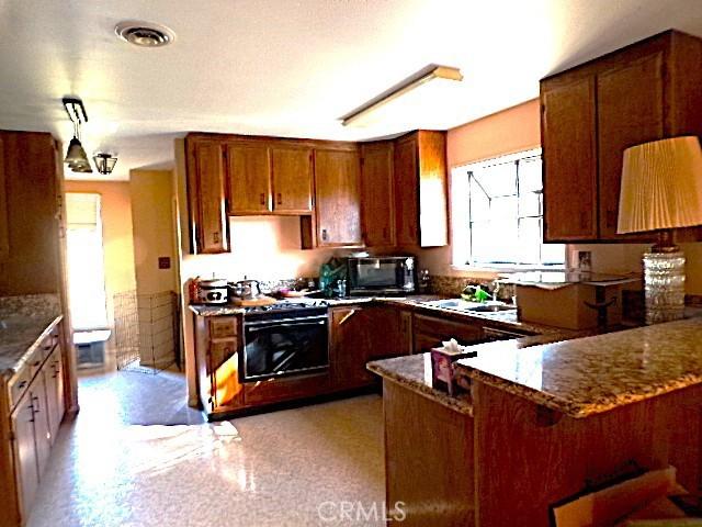 kitchen featuring white stove, sink, stone countertops, wall oven, and kitchen peninsula