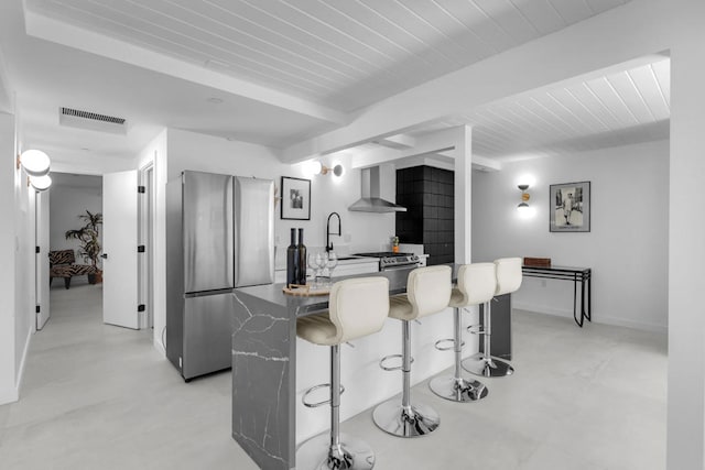 kitchen with wall chimney exhaust hood, stainless steel fridge, a kitchen breakfast bar, and sink