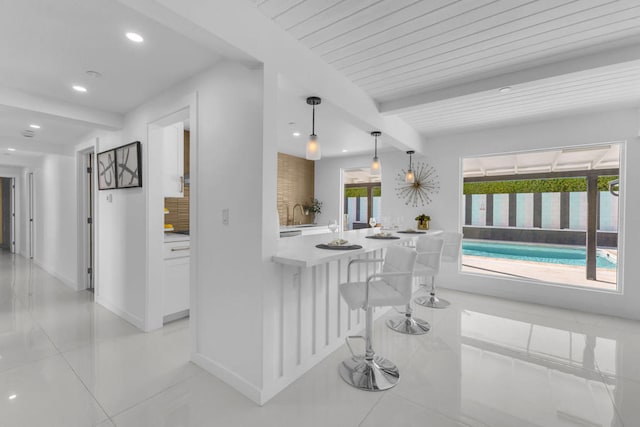 kitchen with hanging light fixtures, beam ceiling, backsplash, and light tile patterned flooring