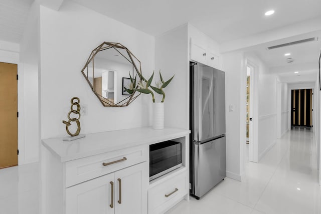 interior space featuring stainless steel appliances, light tile patterned floors, and white cabinets