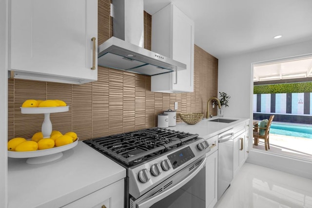 kitchen featuring sink, white cabinets, decorative backsplash, stainless steel appliances, and wall chimney exhaust hood